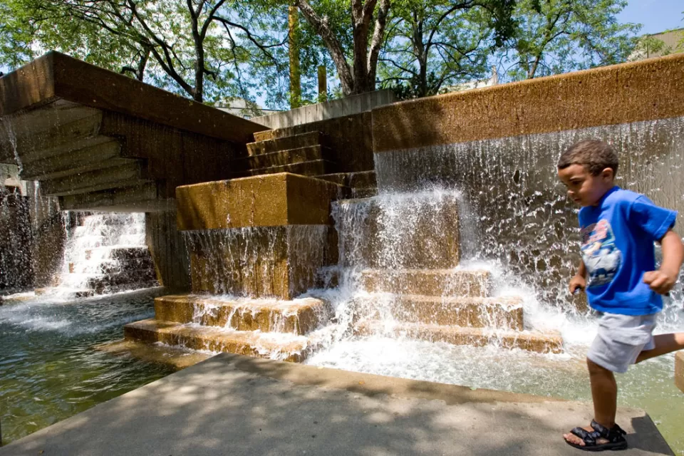 child playing in Peavey Plaza fountain in Minneapolis